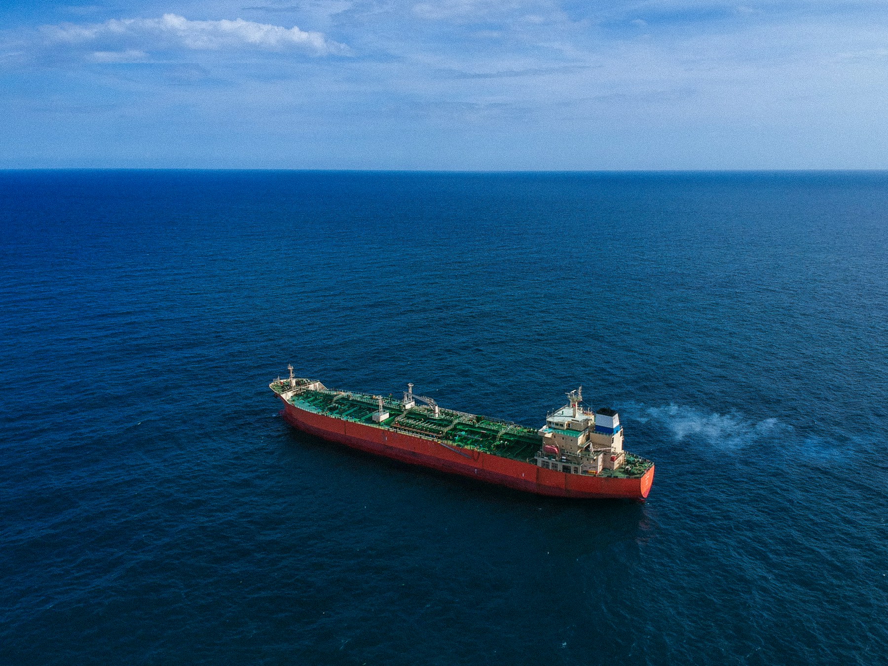 Red-hulled tanker vessel on open blue water